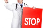 Portrait of senior doctor with warning table.